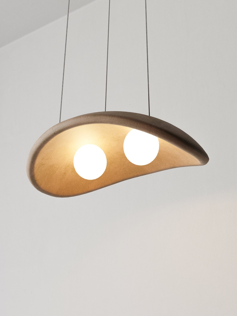 May include: A modern pendant light fixture with a brown, organic-shaped shade and two white globe light bulbs.