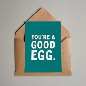 Könnte beinhalten: Eine türkisfarbene Karte mit weißem Text, der "You're a good egg." lautet.