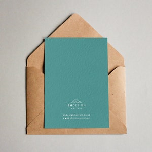 May include: A teal card with a white logo that says "SHDESIGN MALVERN" and the website address "shdesignmalvern.co.uk". The card also includes social media icons for Facebook and Twitter with the handle "@shdesignmalvern". The card is in a brown envelope.