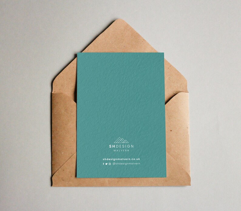 May include: A teal card with a white logo that says "SHDESIGN MALVERN" and the website address "shdesignmalvern.co.uk". The card also includes social media icons for Facebook and Twitter with the handle "@shdesignmalvern". The card is in a brown envelope.