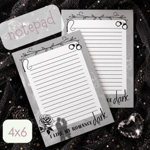 May include: Two rectangular 4x6 inch notepads with gray borders and white lined paper. The top features a vine illustration with handcuffs. The bottom displays a rose, a silhouette of a couple, and the text I LIKE MY ROMANCE dark.
