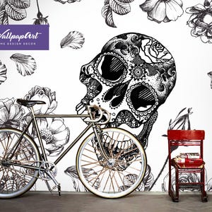 May include: Black and white illustration of a skull with floral details on a white background. A bicycle, a red chair, and a green cabinet with a mirror are in the foreground.