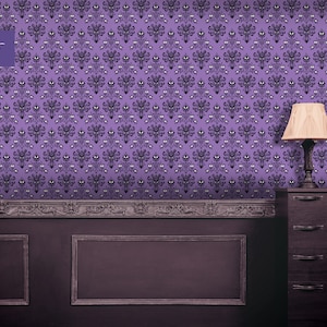 Puede incluir: Papel tapiz morado con un patr&oacute;n repetido de una cara de fantasma. El papel tapiz est&aacute; en una habitaci&oacute;n con molduras de madera oscura y una c&oacute;moda de madera oscura con una l&aacute;mpara en la parte superior.