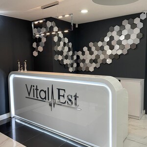 Illuminated desk,  the wall behind the desk features a silver, gray, and black honeycomb pattern of the NORM wall panels.