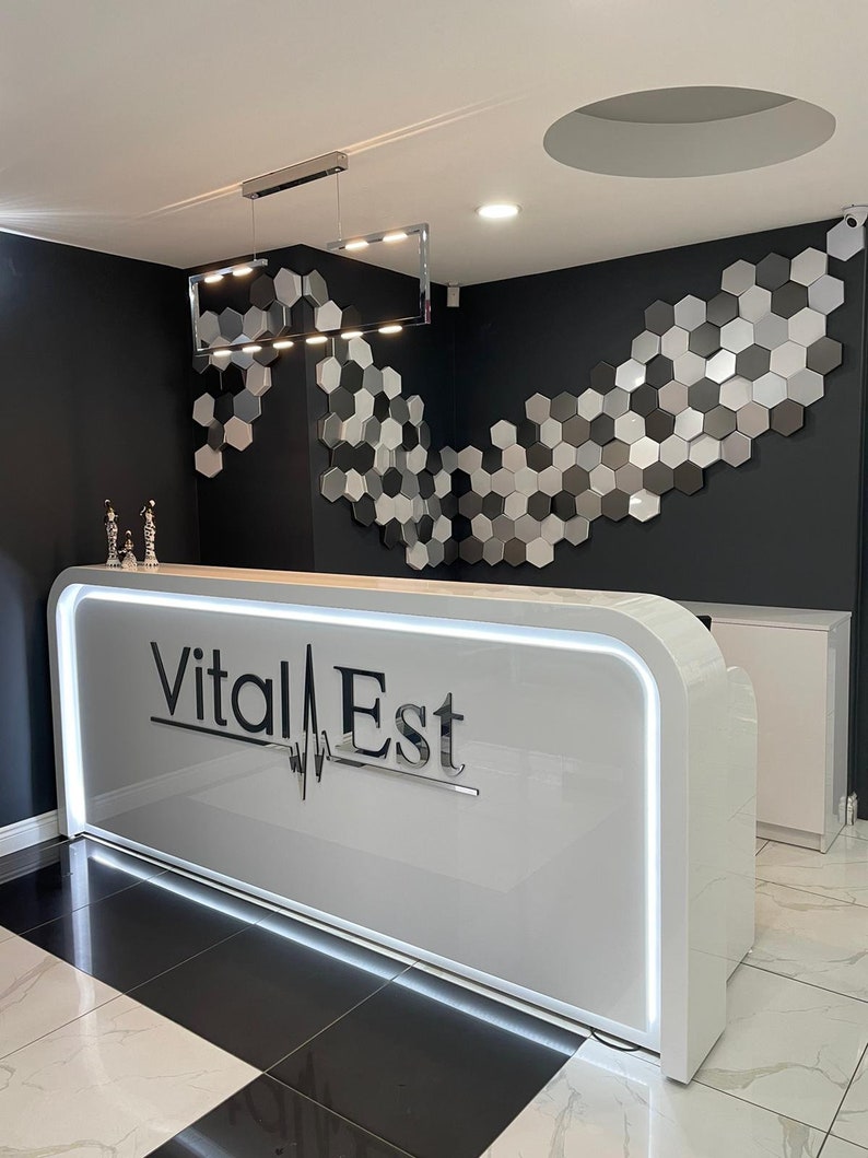 Illuminated desk,  the wall behind the desk features a silver, gray, and black honeycomb pattern of the NORM wall panels.