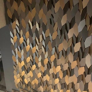 Side-profile view of a staircase wall decorated with 3D polygon tiles, demonstrating how the raised geometric shapes cast shadows under hallway light fixtures.