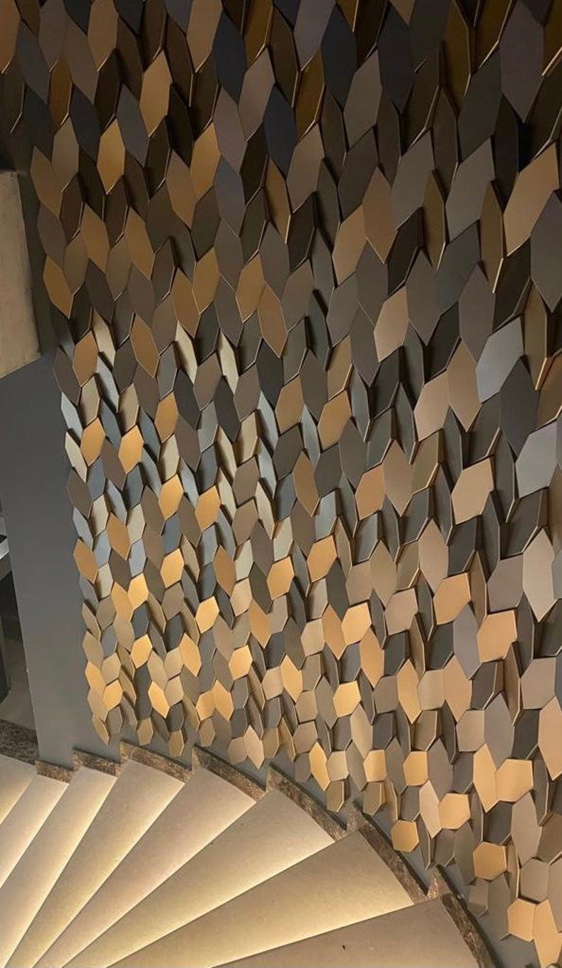 Side-profile view of a staircase wall decorated with 3D polygon tiles, demonstrating how the raised geometric shapes cast shadows under hallway light fixtures.