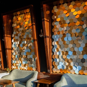 A modern cafe interior featuring NORM honeycomb panels in gold, silver, and blue tones.