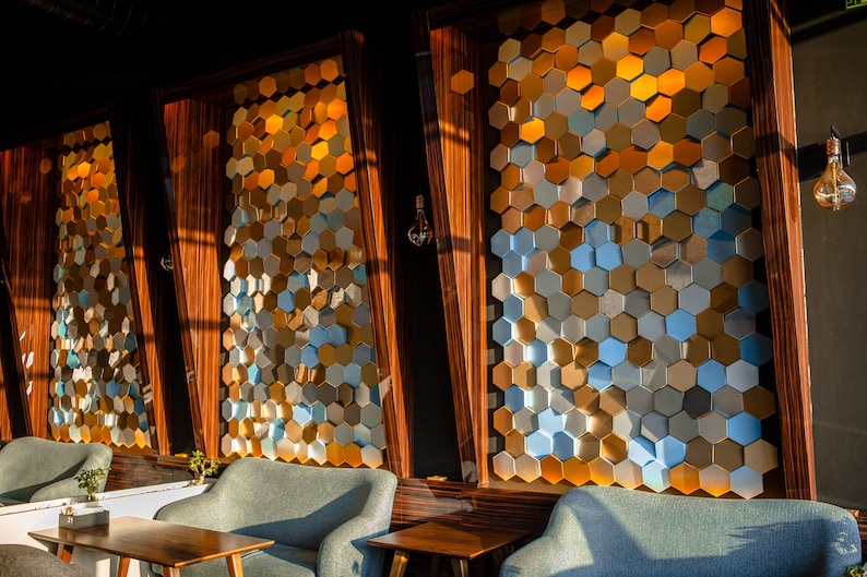 A modern cafe interior featuring NORM honeycomb panels in gold, silver, and blue tones.