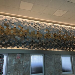 An installation shot showing how NORM 3D hexagonal wall panels seamlessly connect to form a continuous, cohesive geometric surface.