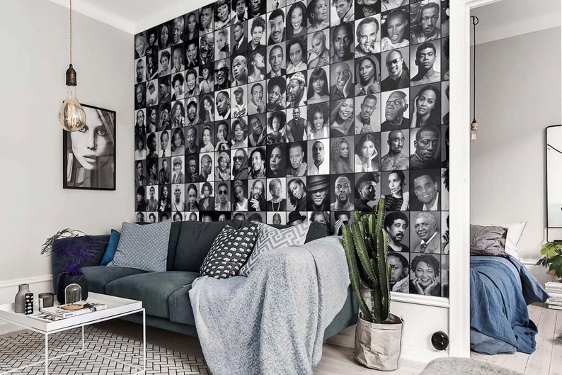 Może przedstawiać: Czarno-biała fotokolaż twarzy znanych os&oacute;b, użyty jako mural ścienny w salonie z szarą sofą, kaktusową rośliną i białym stolikiem kawowym.