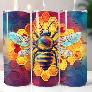 Puede incluir: Tres vasos de acero inoxidable con un diseño colorido de abeja y panal. La abeja es amarilla y negra con alas azules. El panal es amarillo y naranja con un fondo rojo y azul.