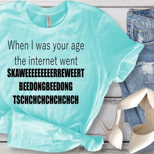 May include: A light blue t-shirt with black text that reads "When I was your age the internet went SKAWEEEEEEEERREWEERT BEEDONGBEEDONG TSCHCHCHCHCHCHCHCH".