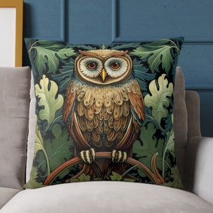 May include: A throw pillow with a dark green background featuring a detailed illustration of an owl perched on a branch. The owl has brown and gold feathers and large, round eyes. The background is filled with green leaves and vines.