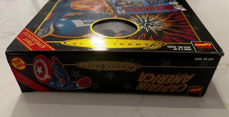 May include: A black box featuring Captain America artwork and the text "Famous Cover". The box has a clear window and the words "First Appearances" are visible. The Marvel Comics logo is also present.