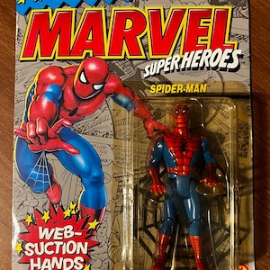 May include: A vintage action figure of Spider-Man from the Marvel Super Heroes line. The figure is in a plastic blister pack with a red and blue costume, web-suction hands, and the text "The Amazing Spider-Man" on the packaging.