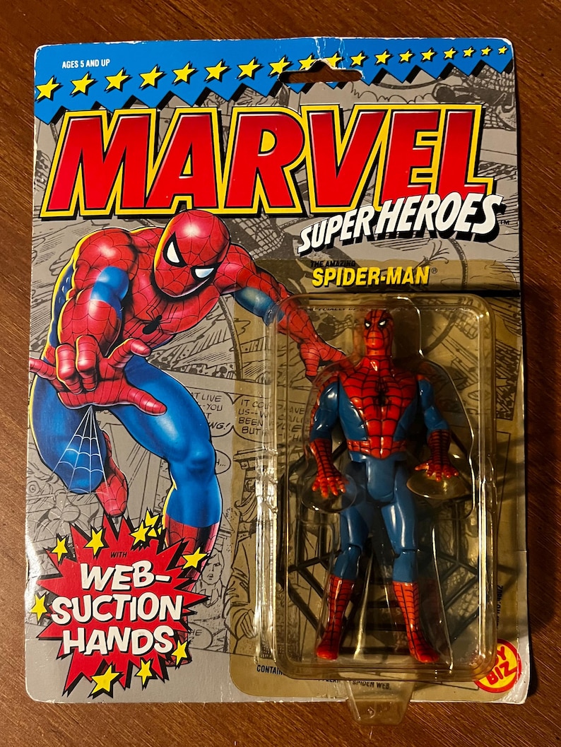 May include: A vintage action figure of Spider-Man from the Marvel Super Heroes line. The figure is in a plastic blister pack with a red and blue costume, web-suction hands, and the text "The Amazing Spider-Man" on the packaging.