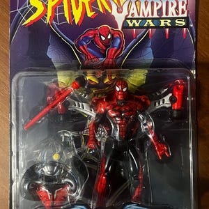 May include: A red and black Spider-Man action figure with a wing attack back pack and missile launcher. The figure is from the Spider-Man Vampire Wars series. The packaging features a black and red background with the Spider-Man Vampire Wars logo.