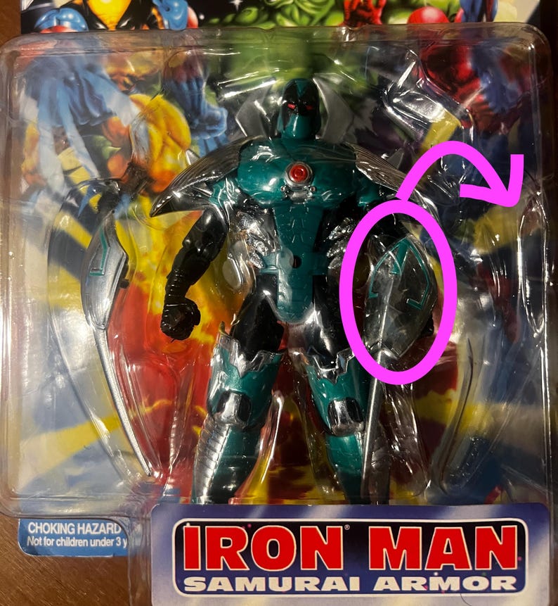 May include: A green and silver action figure of Iron Man in Samurai Armor. The figure has a red eye and a silver sword. The packaging says "Iron Man Samurai Armor".