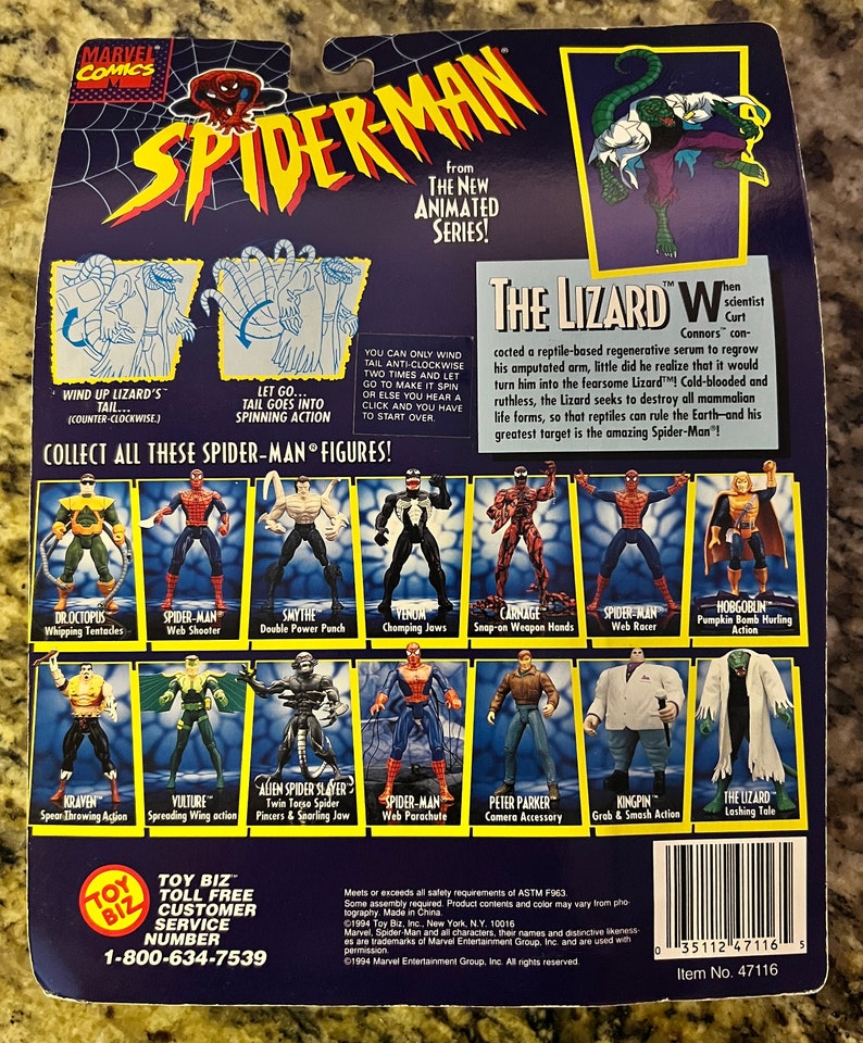 May include: Back of a Spider-Man action figure package. The figure is from the new animated series. The Lizard is the main villain. The package shows the Lizard in a green and white costume. The package also shows other Spider-Man characters, including Venom, Carnage, and Doc Ock. The package is blue and white with the Marvel Comics logo.