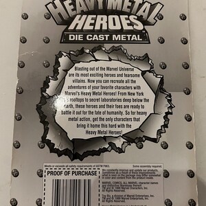 Pode incluir: Parte traseira de uma embalagem de brinquedo de metal fundido Heavy Metal Heroes. A embalagem &eacute; cinza com o logotipo da Marvel Comics e o logotipo da Toy Biz. O texto diz "Heavy Metal Heroes" e inclui uma descri&ccedil;&atilde;o dos recursos do brinquedo.