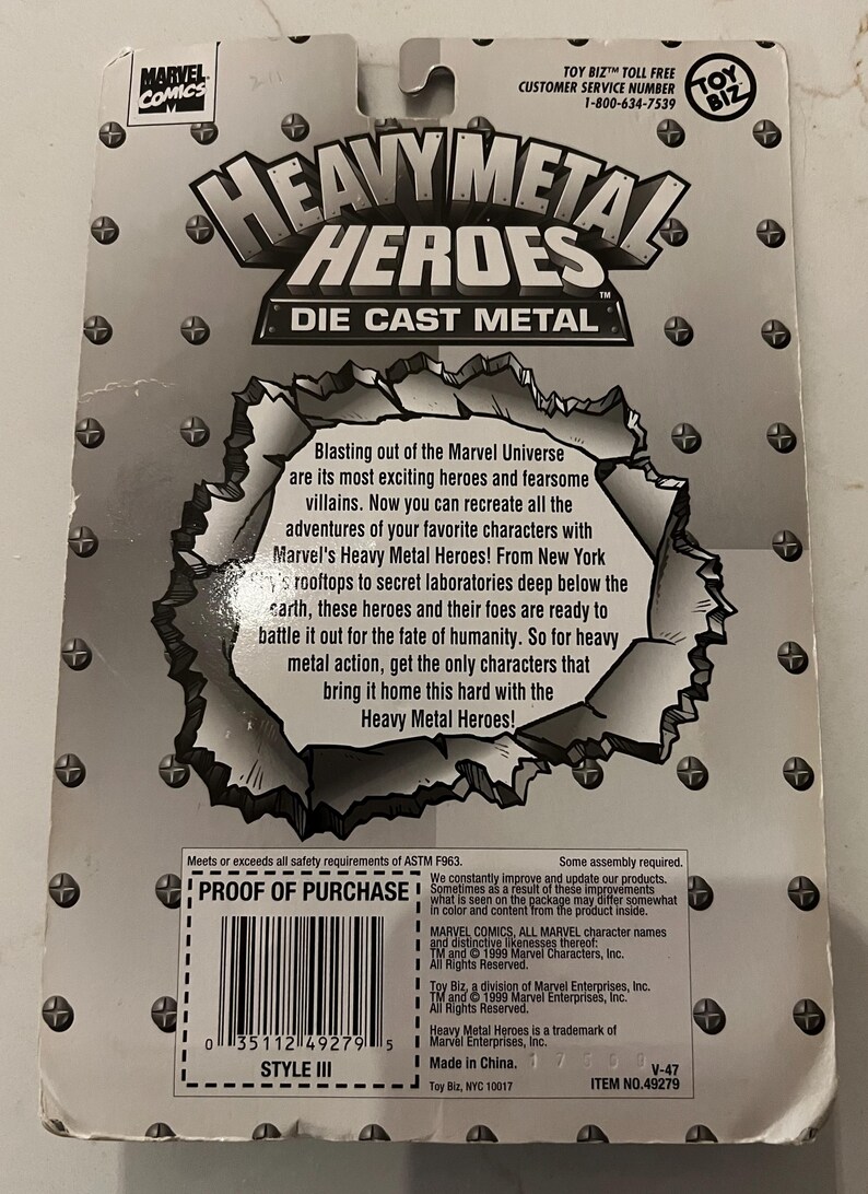 Pode incluir: Parte traseira de uma embalagem de brinquedo de metal fundido Heavy Metal Heroes. A embalagem &eacute; cinza com o logotipo da Marvel Comics e o logotipo da Toy Biz. O texto diz "Heavy Metal Heroes" e inclui uma descri&ccedil;&atilde;o dos recursos do brinquedo.