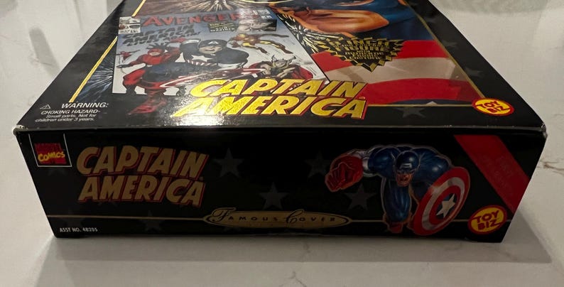 May include: Black box featuring Captain America graphics and text. The box has a comic book cover design with the words "Captain America" in gold lettering. A cartoon image of Captain America is on the side.