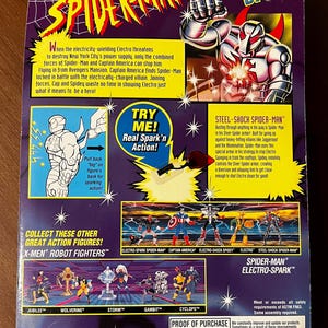 May include: A plastic action figure of Spider-Man wearing a silver and red suit with a metallic sheen. The figure is holding a web shooter in one hand and has a red and blue web coming out of the other hand. The figure is posed in a dynamic action pose. The background is a purple and black design with stars. The text "Spider-Man Electro-Spark" is printed on the packaging.