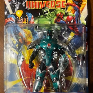 May include: A plastic package containing an action figure of Iron Man in a green and silver Samurai Armor. The figure is posed with a sword in its hand. The package has a red, white, and blue background with the words "Marvel Universe" and "Iron Man Samurai Armor" printed on it.