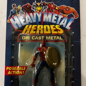 以下が含まれることがあります： マーベルコミックの「ヘビーメタルヒーローズ」スパイダーマンのアクションフィギュア、ダイキャストメタル製。フィギュアは赤と青で、盾を持っています。パッケージにはマーベルコミックのロゴと「Poseable Action！」の文字が含まれています。