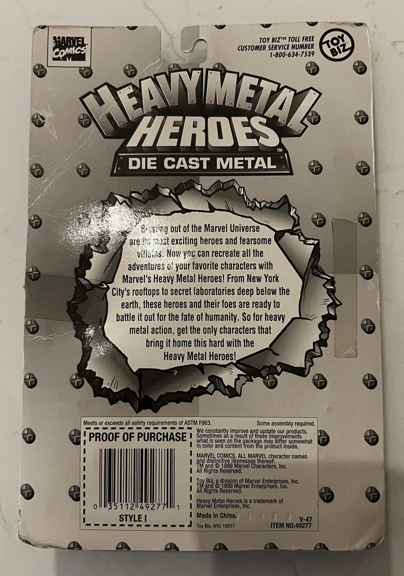 May include: The reverse of a Heavy Metal Heroes die-cast metal toy package. The package features the Marvel Comics logo and the text "Heavy Metal Heroes" in a silver, metallic font. The text describes the characters and their adventures.