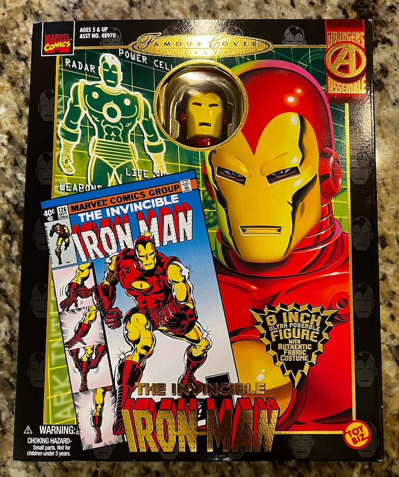 May include: A red and gold Iron Man action figure with a comic book cover featuring the text "The Invincible Iron Man". The figure is 8 inches tall and has an authentic fabric costume. The box is black with gold accents and features the Marvel Comics logo.