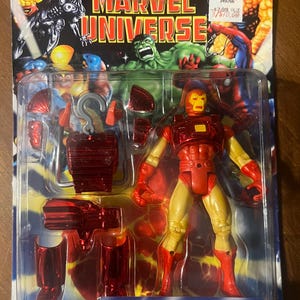May include: Iron Man action figure in red and yellow space armour with a power lift space pack. The figure is packaged in a plastic blister pack with a red and yellow background. The packaging includes the text "Iron Man Space Armour Power Lift Space Pack".