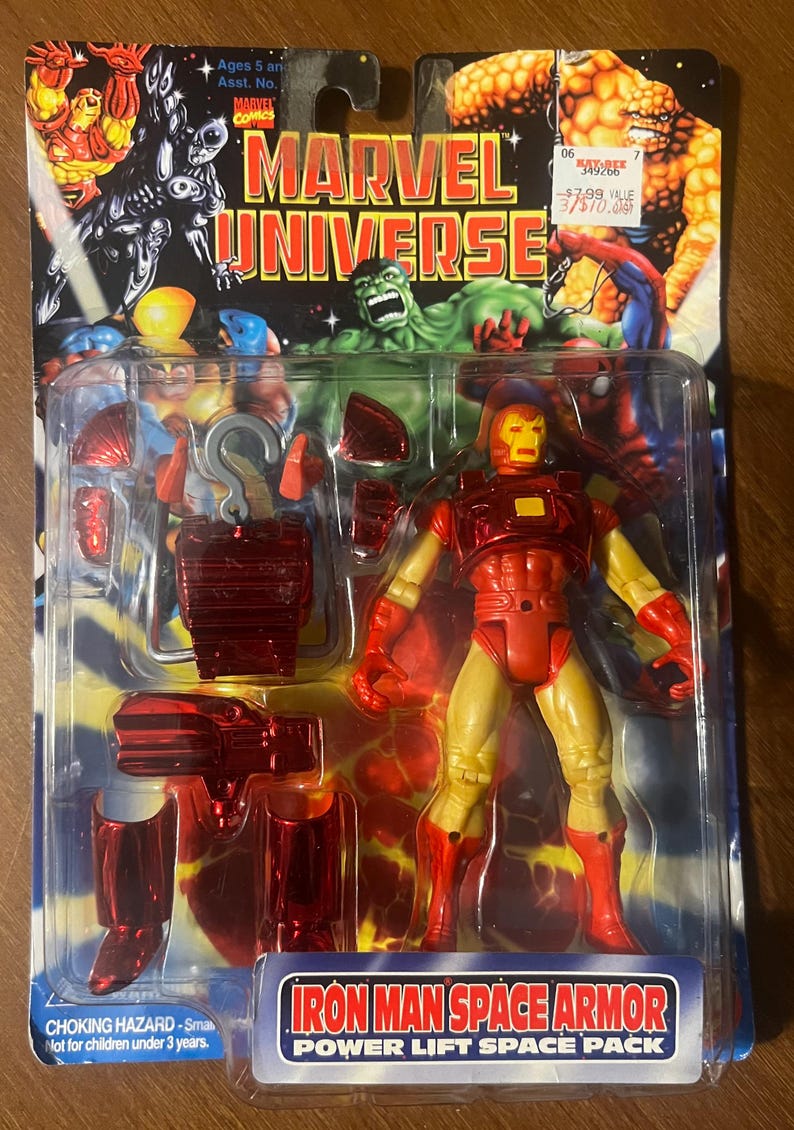 May include: Iron Man action figure in red and yellow space armour with a power lift space pack. The figure is packaged in a plastic blister pack with a red and yellow background. The packaging includes the text "Iron Man Space Armour Power Lift Space Pack".