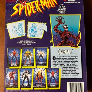 May include: A red and black action figure of Carnage from the Spider-Man animated series. The figure has a red and black costume with a white spider symbol on the chest. The figure is holding a weapon in its right hand. The figure is standing on a blue background. The figure is part of a set of action figures from the Spider-Man animated series. The back of the packaging features a description of the character Carnage. The packaging also features a toll-free customer service number for Toy Biz.