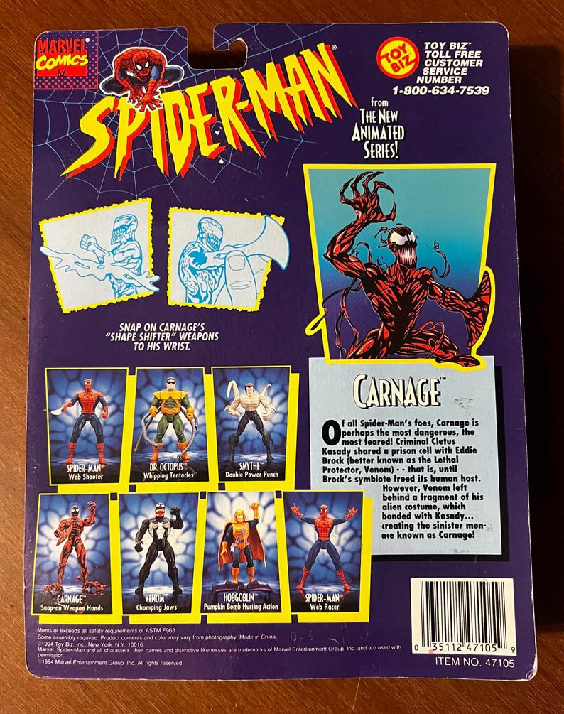 May include: A red and black action figure of Carnage from the Spider-Man animated series. The figure has a red and black costume with a white spider symbol on the chest. The figure is holding a weapon in its right hand. The figure is standing on a blue background. The figure is part of a set of action figures from the Spider-Man animated series. The back of the packaging features a description of the character Carnage. The packaging also features a toll-free customer service number for Toy Biz.