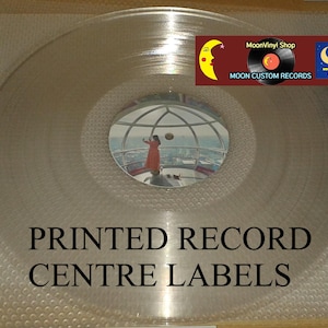 K&ouml;nnte beinhalten: Eine transparente Schallplatte mit reflektierender Oberfl&auml;che. Das Label in der Mitte zeigt ein Spiegelbild einer Person in einem orangefarbenen Kleid. Der Text "PRINTED RECORD CENTRE LABELS" ist darunter gedruckt. Ein Logo mit Mond und "MoonVinyl Shop" befindet sich oben rechts.