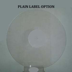 K&ouml;nnte beinhalten: Eine transparente Schallplatte mit einem wei&szlig;en Label in der Mitte. Der Text "PLAIN LABEL OPTION" ist oben aufgedruckt. Die Schallplatte wird auf einem transparenten St&auml;nder pr&auml;sentiert.