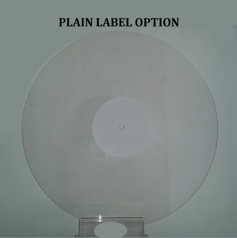 K&ouml;nnte beinhalten: Eine transparente Schallplatte mit einem wei&szlig;en Label in der Mitte. Der Text "PLAIN LABEL OPTION" ist oben aufgedruckt. Die Schallplatte wird auf einem transparenten St&auml;nder pr&auml;sentiert.
