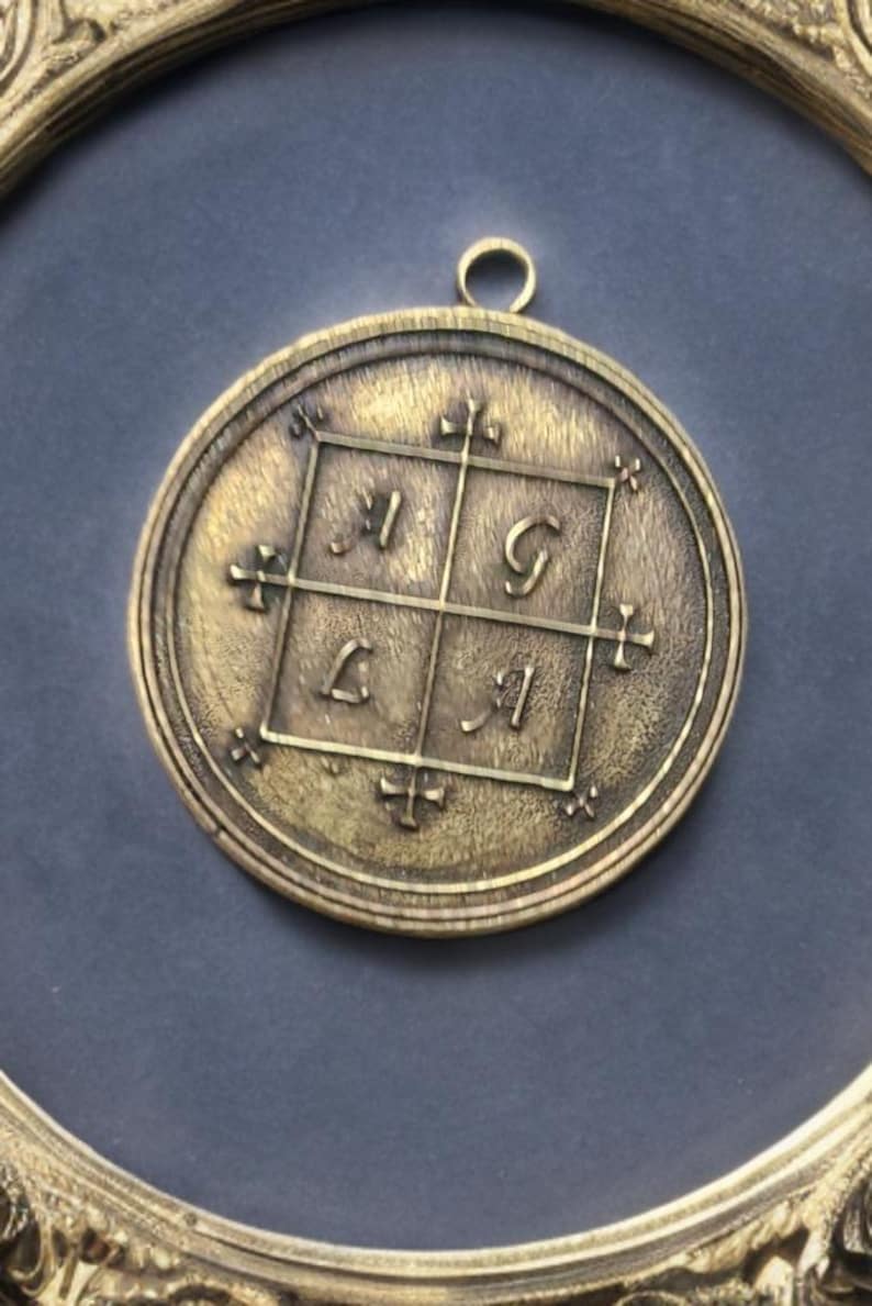 May include: A brass pendant with a square design featuring the letters "I", "G", "L", and "I" in a grid pattern. The pendant is surrounded by a circular frame with decorative details.