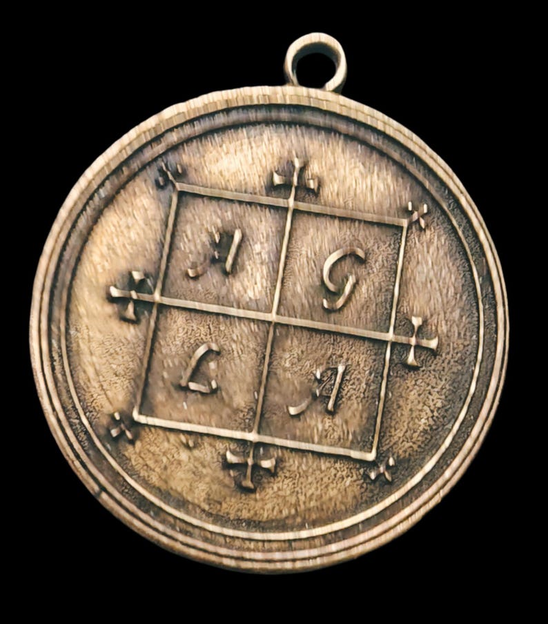 May include: A round, bronze pendant with a square design featuring the letters 'I', 'G', 'L', and 'I' in a grid pattern. The pendant has a loop at the top for hanging.