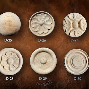 Puede incluir: Seis elementos decorativos circulares de madera sin terminar. Cada uno presenta diseños tallados variados, incluyendo patrones florales y círculos concéntricos. Cada pieza está etiquetada con una "D" seguida de un número, como "D-25" y "D-26".