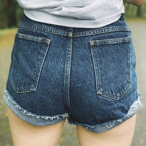 May include: A pair of blue denim shorts with frayed edges and back pockets.