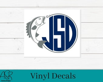May include: A navy blue and gray monogram with the letters JSD inside a circle. A gray fish is jumping out of the circle with a fishing hook in its mouth.