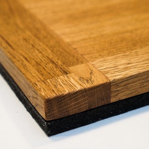 May include: Close-up of a wooden tabletop with a parquet pattern. The tabletop is made of light brown wood and has a dark brown border. The tabletop is sitting on a black surface.