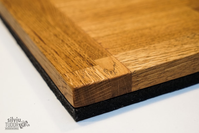 May include: Close-up of a wooden tabletop with a parquet pattern. The tabletop is made of light brown wood and has a dark brown border. The tabletop is sitting on a black surface.