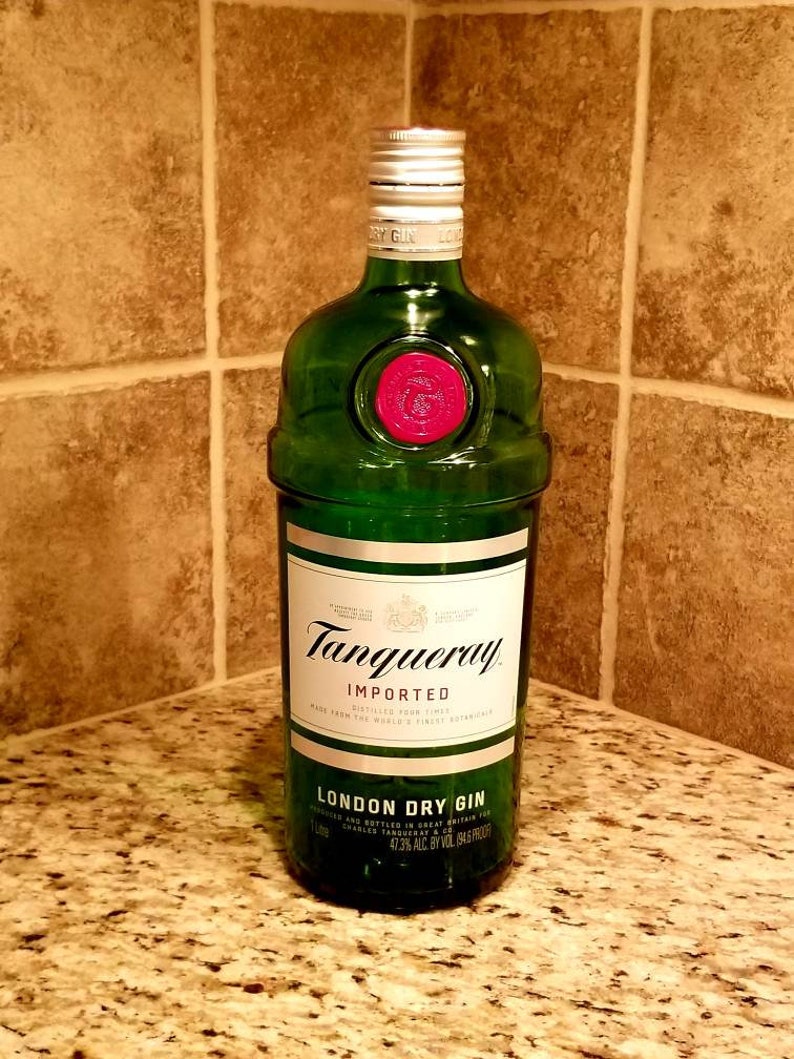 May include: A green glass bottle of Tanqueray London Dry Gin. The bottle has a white label with black text and a red seal. The bottle is 1 liter and 47.3% ABV.