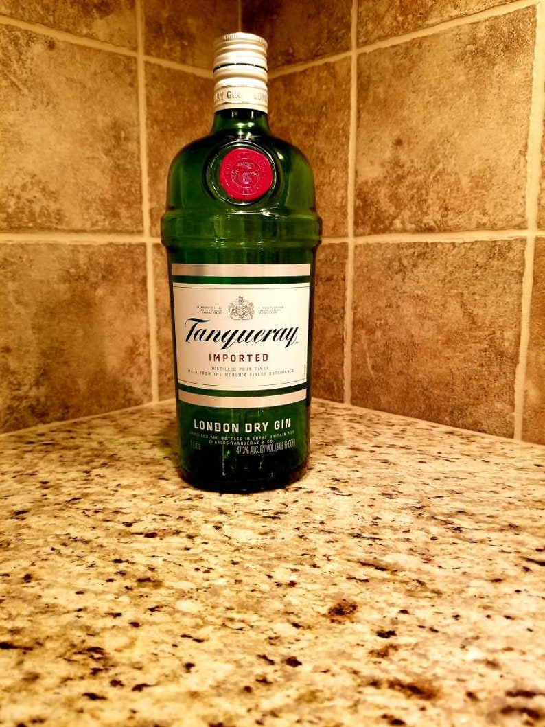 May include: A green glass bottle of Tanqueray London Dry Gin, with a red wax seal and a silver cap. The label reads "Tanqueray Imported London Dry Gin". The bottle is on a granite countertop.
