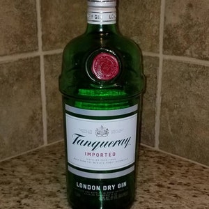 May include: A green glass bottle of Tanqueray London Dry Gin. The bottle has a silver cap and a white label with black text. The label reads "Tanqueray Imported London Dry Gin". A red seal is visible near the top of the bottle.