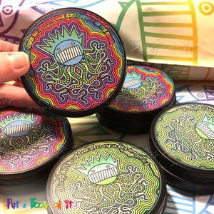 May include: Several round, black-lidded containers with vibrant, psychedelic designs. Each container displays a cartoon octopus with a crown and the text "...tentacles expanding in my mind!" in a rainbow of colours.